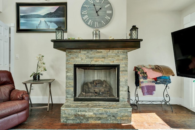 interior space with a stone fireplace and dark hardwood / wood-style floors