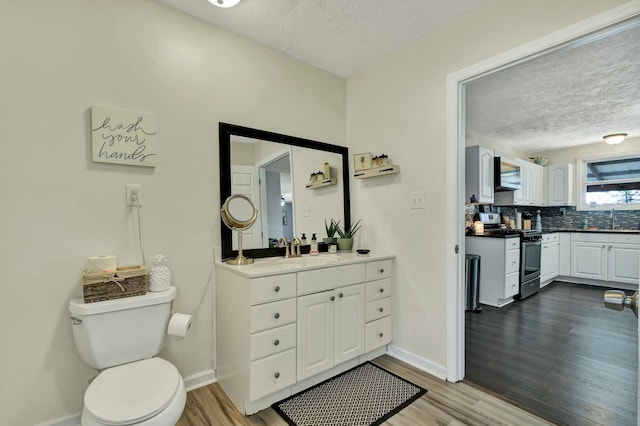 bathroom featuring vanity, decorative backsplash, toilet, a textured ceiling, and wood-type flooring