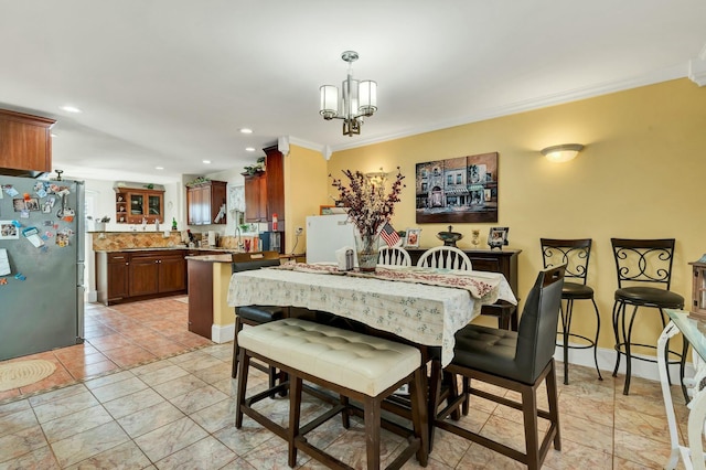 dining area with sink, an inviting chandelier, and ornamental molding