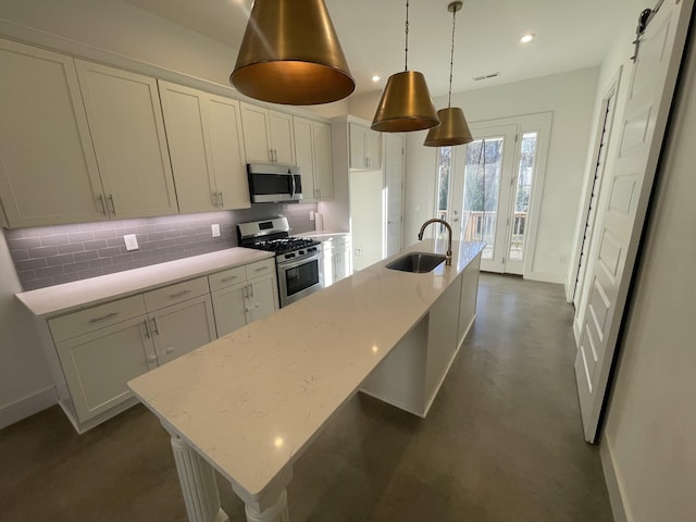 kitchen with a kitchen island with sink, sink, decorative light fixtures, and appliances with stainless steel finishes