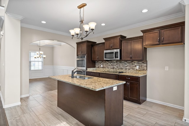 kitchen with hanging light fixtures, light stone counters, sink, and appliances with stainless steel finishes