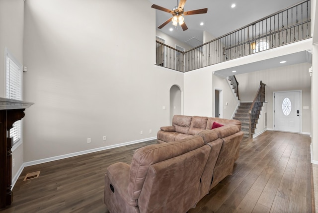 living room with a high ceiling, dark hardwood / wood-style flooring, and ceiling fan