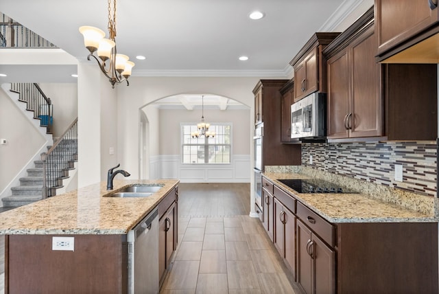 kitchen featuring decorative light fixtures, light stone counters, sink, and appliances with stainless steel finishes