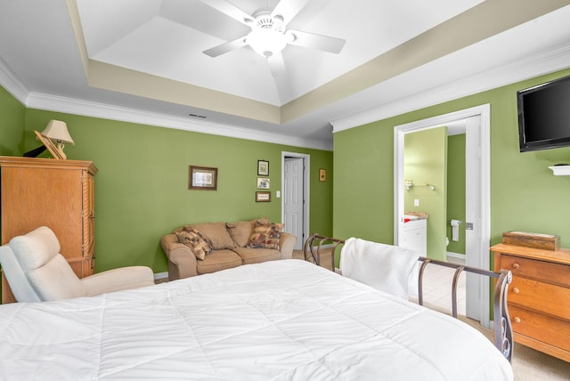 carpeted bedroom with ensuite bathroom, ceiling fan, crown molding, and a tray ceiling