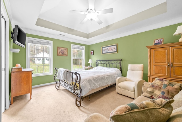 carpeted bedroom with a tray ceiling, ceiling fan, and ornamental molding