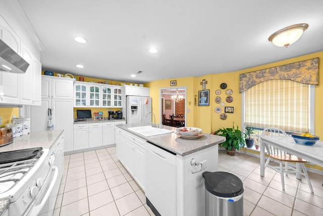 kitchen with white cabinetry, sink, an island with sink, white appliances, and light tile patterned floors