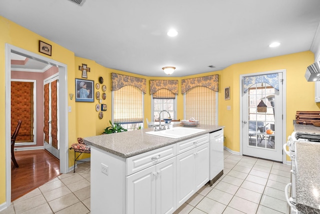 kitchen with dishwasher, ornamental molding, an island with sink, white cabinets, and range