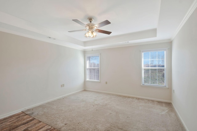 carpeted empty room featuring a tray ceiling, crown molding, and ceiling fan