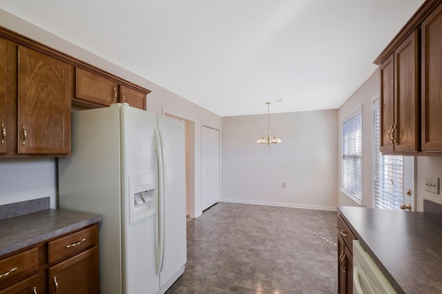 kitchen featuring dishwashing machine, a chandelier, hanging light fixtures, and white refrigerator with ice dispenser