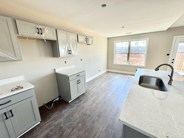 kitchen featuring light stone countertops, sink, gray cabinetry, and dark hardwood / wood-style flooring