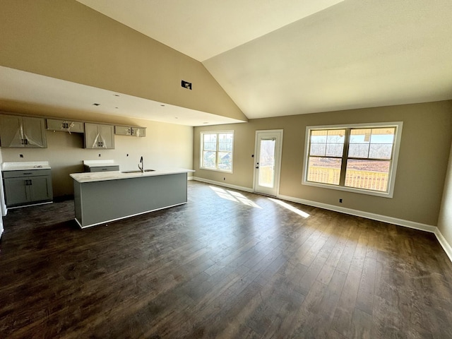 unfurnished living room with dark wood-type flooring, high vaulted ceiling, and sink