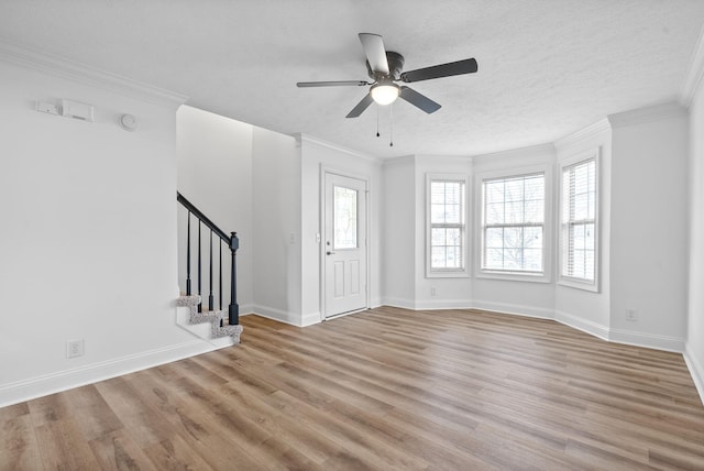 interior space featuring a textured ceiling, ceiling fan, light wood-type flooring, and ornamental molding