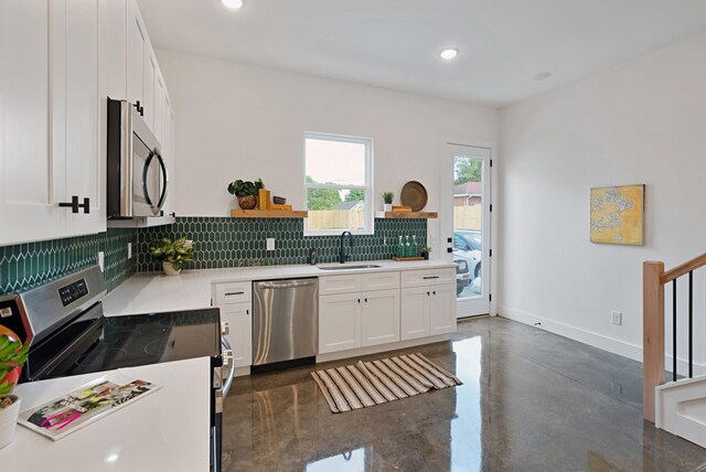 kitchen with white cabinets, sink, stainless steel appliances, and tasteful backsplash