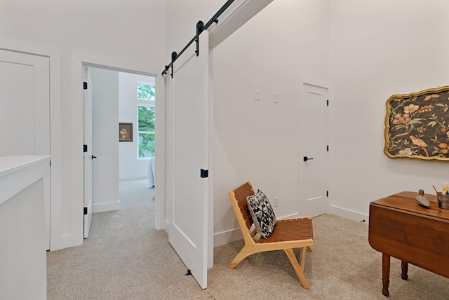 sitting room with a barn door and light colored carpet