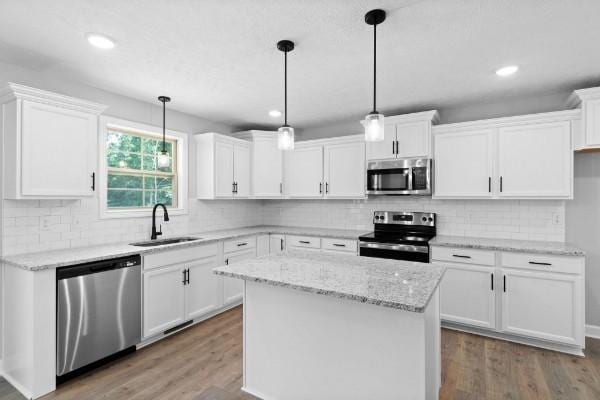 kitchen with white cabinets, stainless steel appliances, a kitchen island, and sink