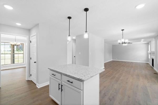 kitchen featuring light stone counters, white cabinetry, wood-type flooring, and decorative light fixtures