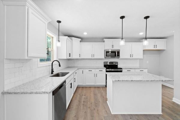 kitchen featuring sink, white cabinetry, stainless steel appliances, and hanging light fixtures