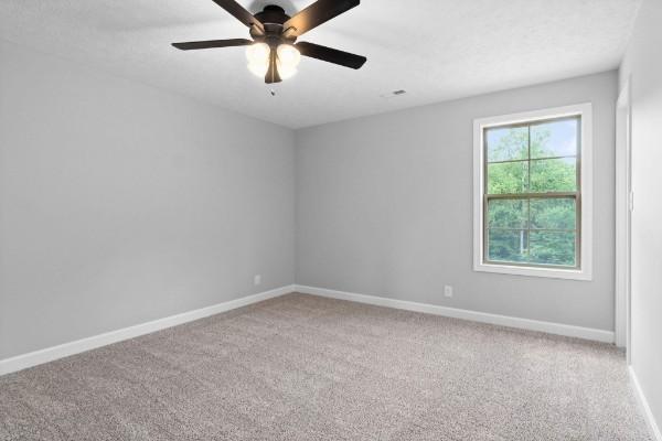 carpeted spare room with ceiling fan