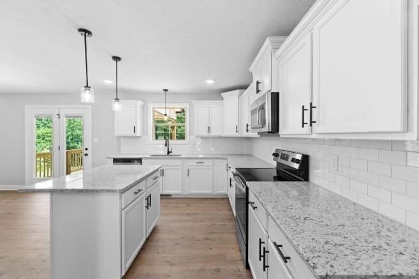 kitchen with electric range, a kitchen island, and white cabinetry