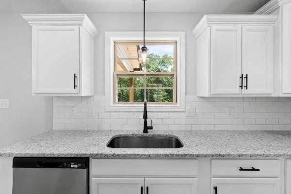 kitchen featuring stainless steel dishwasher, white cabinets, light stone countertops, and sink