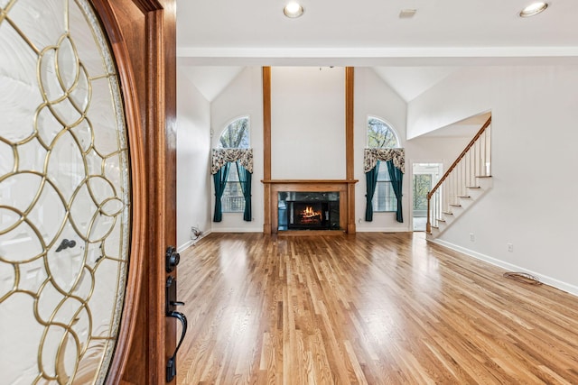 unfurnished living room featuring a premium fireplace, light wood-type flooring, and vaulted ceiling