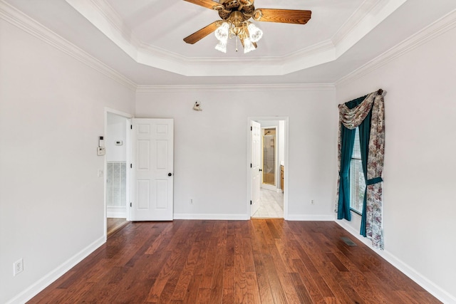 unfurnished room with dark wood-type flooring, a raised ceiling, ceiling fan, and ornamental molding