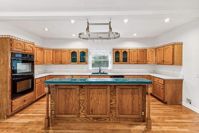 kitchen featuring a breakfast bar, a kitchen island, light hardwood / wood-style floors, and double oven