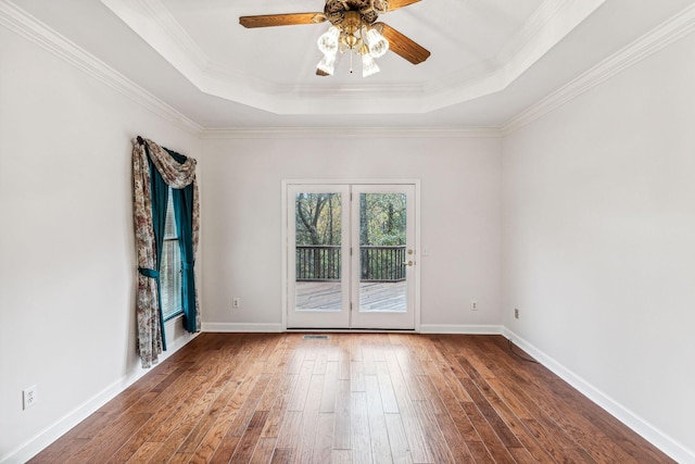 empty room with a raised ceiling, crown molding, ceiling fan, and dark hardwood / wood-style floors