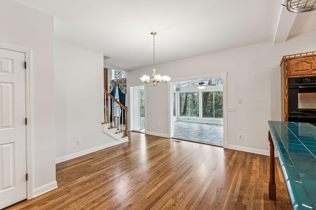 unfurnished dining area with hardwood / wood-style flooring, ceiling fan with notable chandelier, and beam ceiling