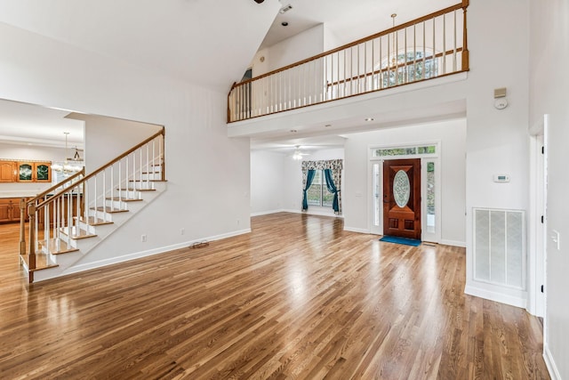 entryway with wood-type flooring, high vaulted ceiling, and an inviting chandelier