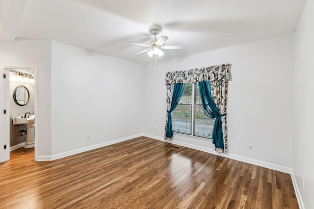 unfurnished bedroom with wood-type flooring, connected bathroom, ceiling fan, and sink