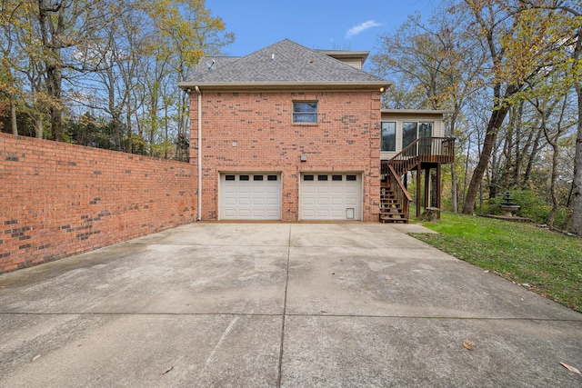 view of property exterior with a garage, a lawn, and a wooden deck