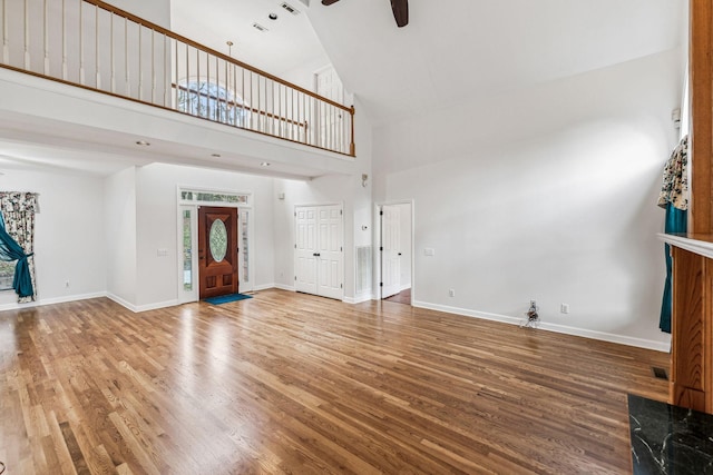 unfurnished living room with ceiling fan, wood-type flooring, and high vaulted ceiling