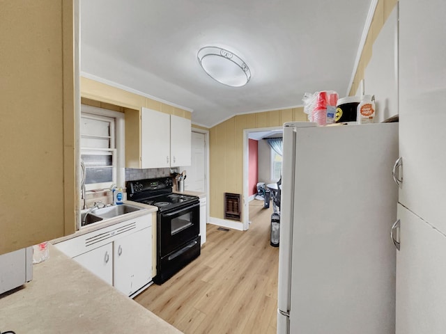 kitchen featuring heating unit, white refrigerator, white cabinetry, and black electric range