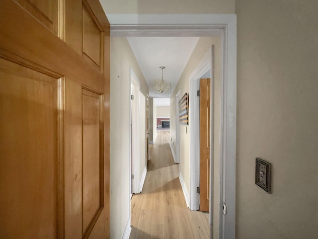 hallway with a chandelier and light wood-type flooring