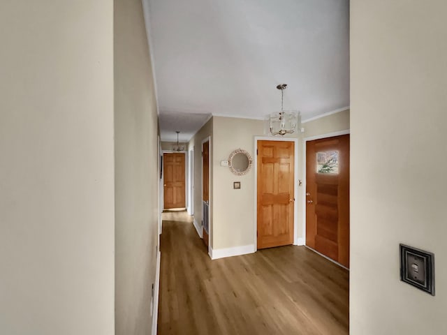 entryway featuring hardwood / wood-style flooring, ornamental molding, and an inviting chandelier