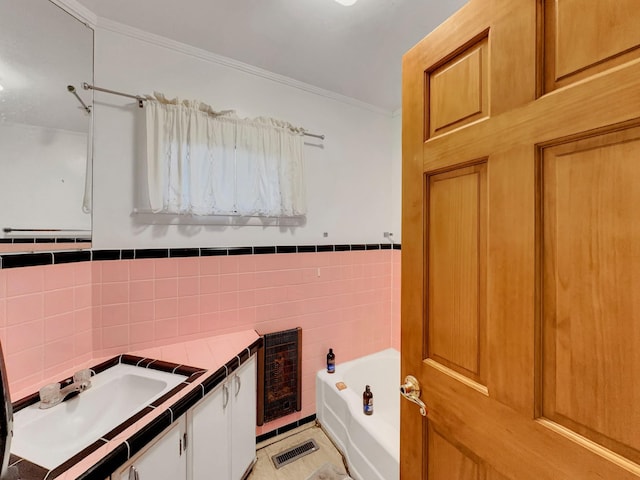 bathroom featuring vanity, a tub to relax in, crown molding, and tile walls