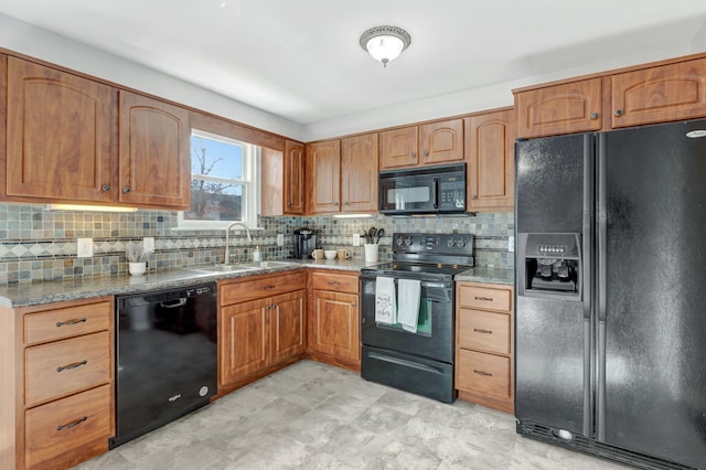 kitchen featuring black appliances, decorative backsplash, light stone counters, and sink