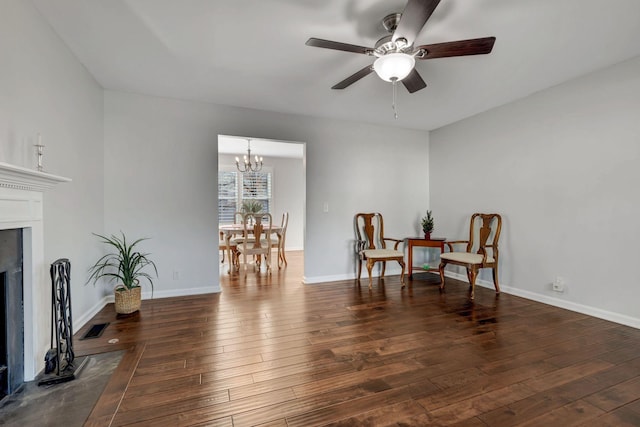 sitting room with ceiling fan with notable chandelier and dark hardwood / wood-style floors