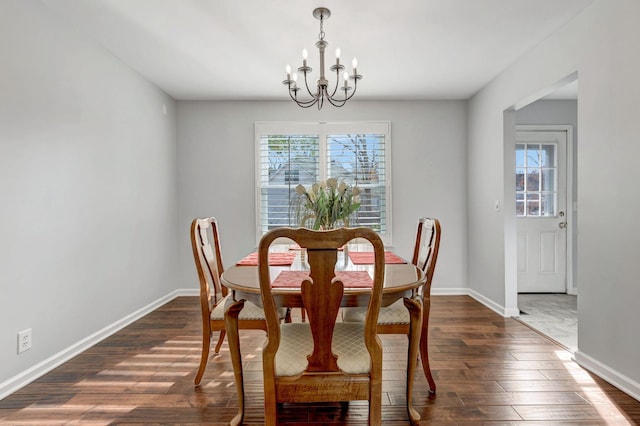 dining area featuring dark wood-type flooring, a healthy amount of sunlight, and a notable chandelier