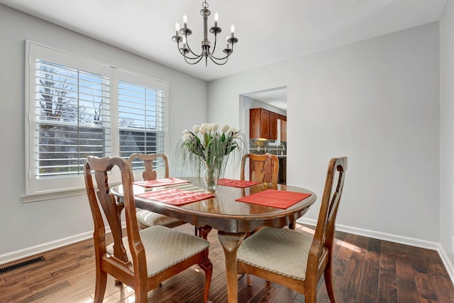 dining room with dark hardwood / wood-style flooring and a notable chandelier