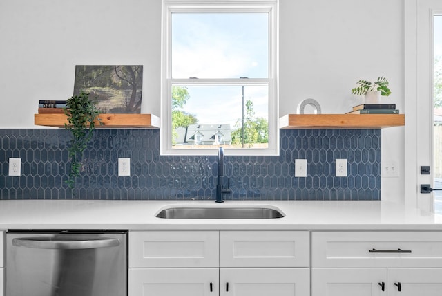 kitchen with white cabinets, decorative backsplash, stainless steel dishwasher, and sink