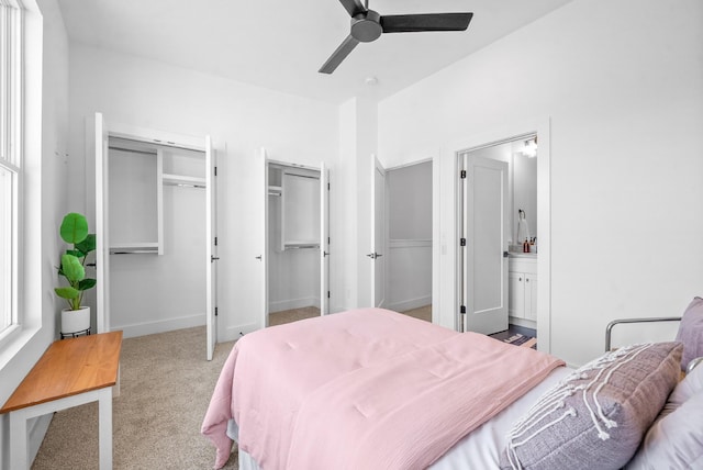 carpeted bedroom featuring ceiling fan, connected bathroom, and two closets