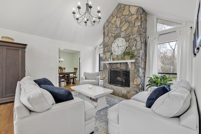 living room with a fireplace, high vaulted ceiling, a chandelier, and light hardwood / wood-style flooring