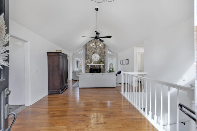 living room featuring hardwood / wood-style flooring, ceiling fan, a fireplace, and vaulted ceiling