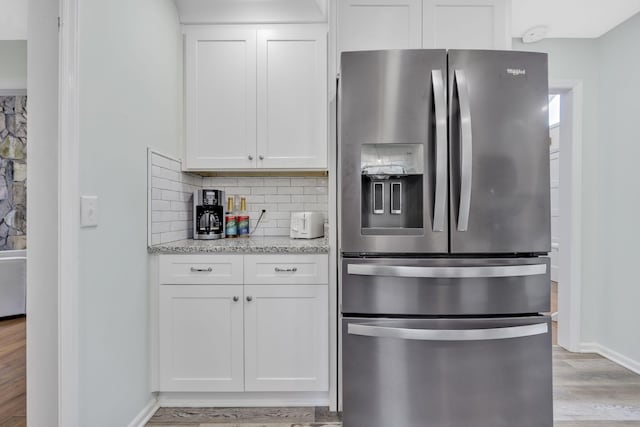 kitchen featuring light stone counters, white cabinetry, light hardwood / wood-style floors, and stainless steel refrigerator with ice dispenser