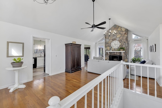 living room featuring lofted ceiling, ceiling fan, wood-type flooring, and a fireplace