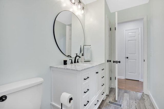 bathroom with toilet, vanity, and hardwood / wood-style flooring