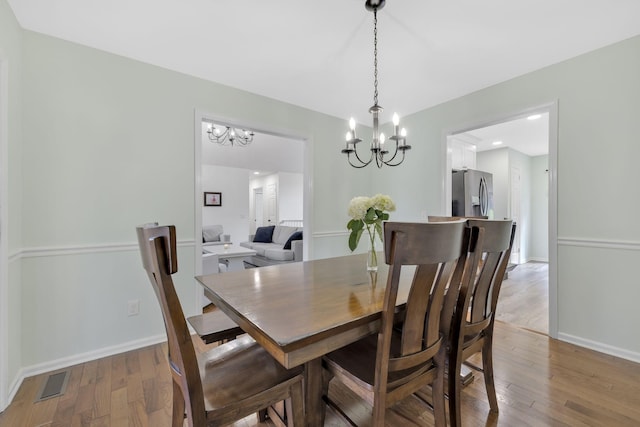 dining room featuring wood-type flooring and an inviting chandelier