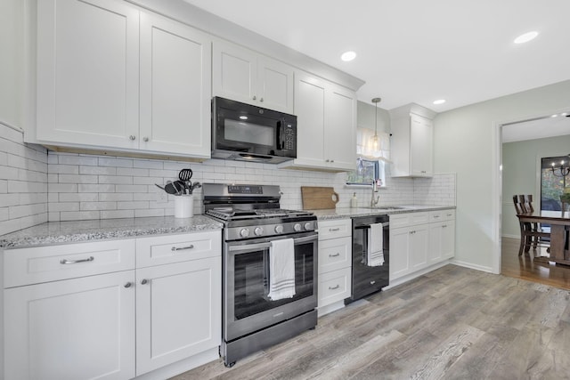 kitchen with black appliances, plenty of natural light, light hardwood / wood-style floors, and decorative light fixtures